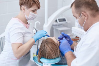 Doktor dişçi genç ve güzel bir kızın dişlerini tedavi ediyor. Dişçinin resepsiyonundaki kız. Doktor dişçi dişleri tedavi eder.