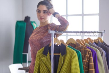 Pano raf giysi tasarımcısı ile yakınındaki beyaz arka plan üzerinde tutan güzel genç stilist