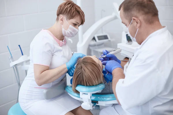 Lekarz dentysta leczy zęby pięknej młodej pacjentki. Dziewczyna z recepcji u dentysty. Lekarz dentysta leczy zęby. — Zdjęcie stockowe
