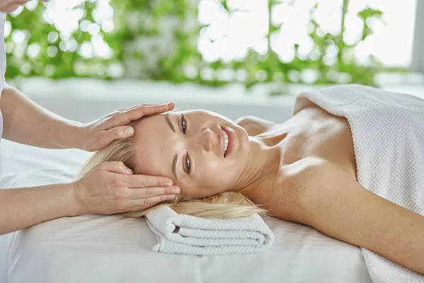 Belle femme aux yeux fermés se faisant masser dans le salon de spa — Photo