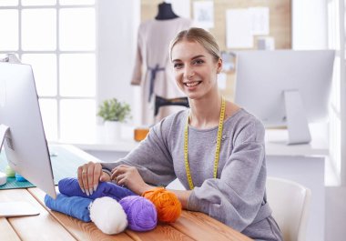 Masasında dikiş makinesi olan bir fabrikada genç ve güzel bir kız.