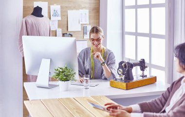 Ofiste çalışan, masaya yaslanan, çizim çeken çekici moda tasarımcısı