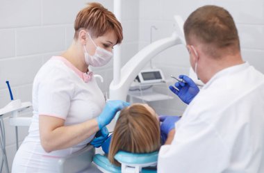 Doktor dişçi genç ve güzel bir kızın dişlerini tedavi ediyor. Dişçinin resepsiyonundaki kız. Doktor dişçi dişleri tedavi eder.