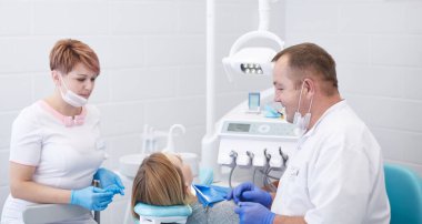 Doktor dişçi genç ve güzel bir kızın dişlerini tedavi ediyor. Dişçinin resepsiyonundaki kız. Doktor dişçi dişleri tedavi eder.