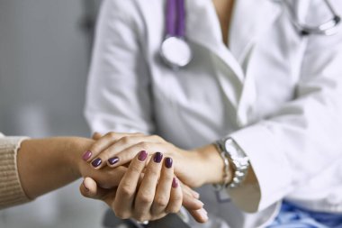 Kadın doktor hastayı sakinleştirir ve elini tutar
