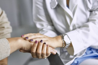 Kadın doktor hastayı sakinleştirir ve elini tutar
