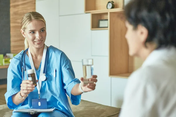 Schöne lächelnde Frau der Arzt in einer Flasche Pille bietet dem Patienten — Stockfoto