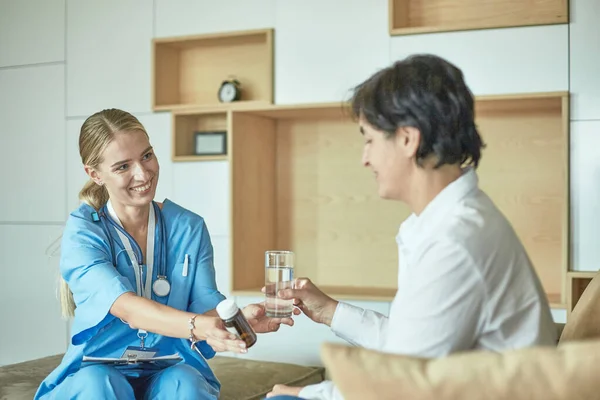 Schöne lächelnde Frau der Arzt in einer Flasche Pille bietet dem Patienten — Stockfoto