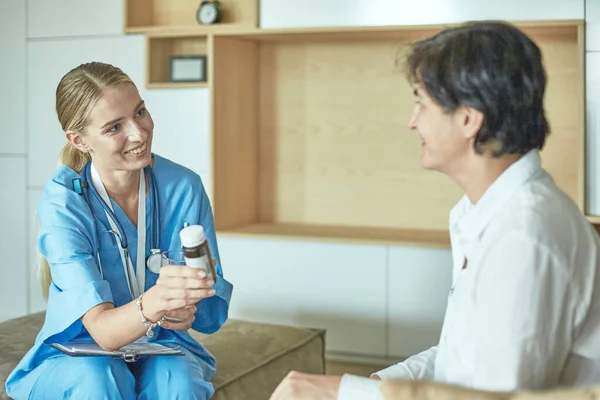 Schöne lächelnde Frau der Arzt in einer Flasche Pille bietet dem Patienten — Stockfoto