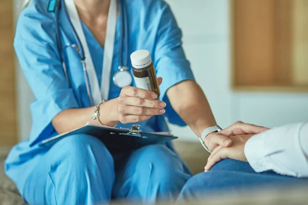 Schöne lächelnde Frau der Arzt in einer Flasche Pille bietet dem Patienten — Stockfoto