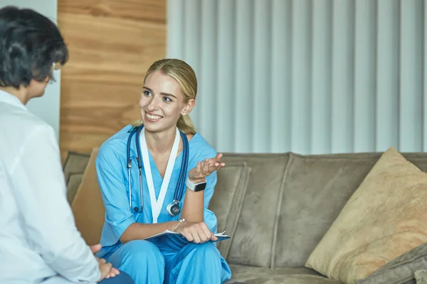 Freundlich lächelnder Arzt und Patient auf dem Sofa sitzend. sehr gute Nachrichten und medizinisches Versorgungskonzept auf hohem Niveau. — Stockfoto