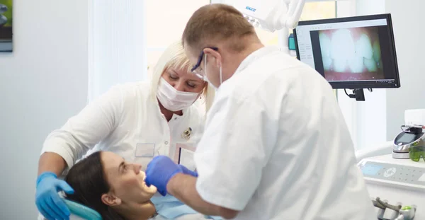 Doctor dentist treats teeth of a beautiful young girl patient. The girl on reception at the dentist. Doctor dentist treats tooth — Stock Photo, Image