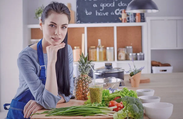 Glückliche junge Frau in der Küche mit frischem Gemüse auf dem Tisch — Stockfoto