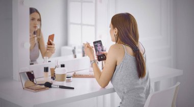 İnanılmaz genç kadın ayna önünde makyaj yapıyor. Portra