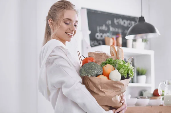 Ung kvinna med livsmedelsbutiker shoppingväska med grönsaker talerätt — Stockfoto