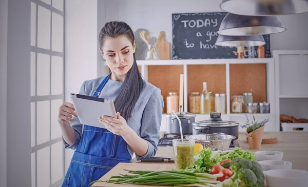 Happy woman looking recipe tablet kitchen reading cooking