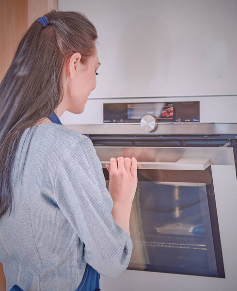 Beautiful woman in the kitchen, waiting with the front of the o