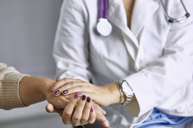 Kadın doktor hastayı sakinleştirir ve elini tutar