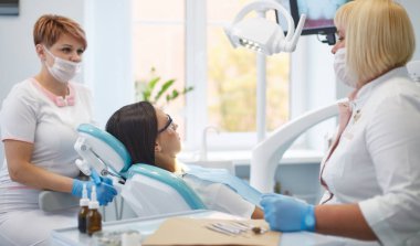Doctor dentist treats teeth of a beautiful young girl patient.