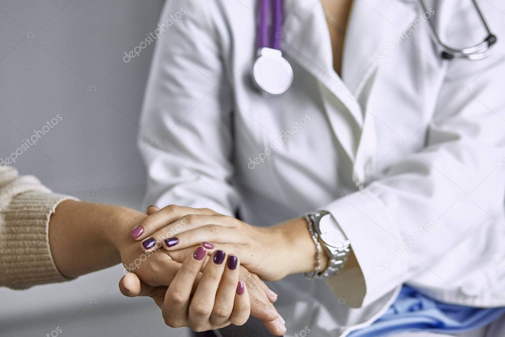 Woman doctor calms patient and holds hand