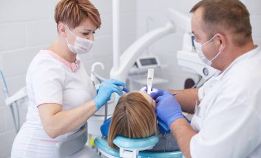 Doctor dentist treats teeth of a beautiful young girl patient.