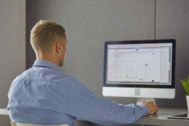 Ofiste çalışan genç bir işadamı, masada oturuyor,