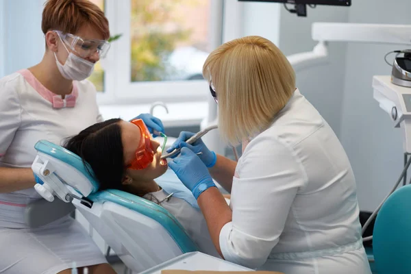 Doctor dentist treats teeth of a beautiful young girl patient.