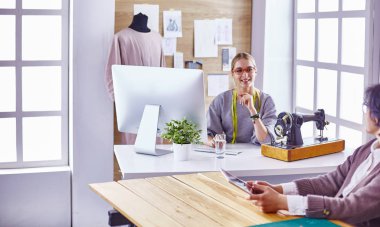 Ofiste çalışan, masaya yaslanan çekici moda tasarımcısı,