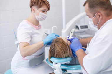Doctor dentist treats teeth of a beautiful young girl patient.