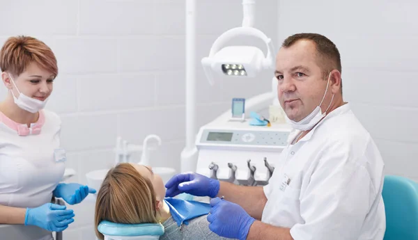 Médico dentista trata los dientes de una hermosa joven paciente . — Foto de Stock