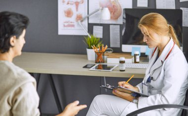 Genç bayan doktor hastasını ofise alıyor.