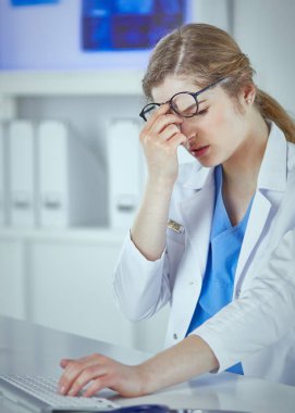Genç kadın doktor bilgisayar ile çalıştıktan sonra yorgun