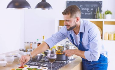 Gülümseyen ve kendinden emin şef büyük mutfakta duruyor.