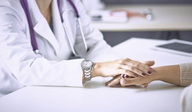 Kadın doktor hastayı sakinleştirir ve elini tutar