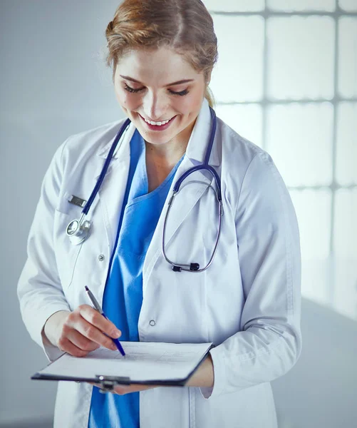 Jeune femme médecin est debout avec planche avec presse-papiers smilin — Photo