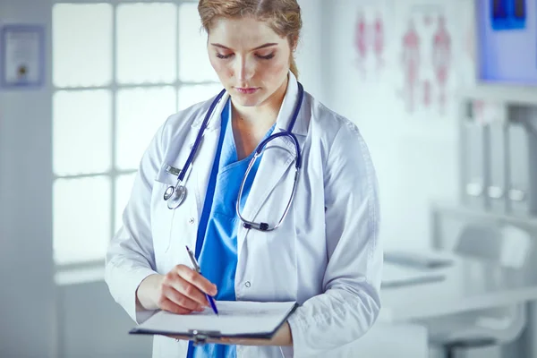 Giovane donna medico è in piedi con bordo con appunti smilin — Foto Stock