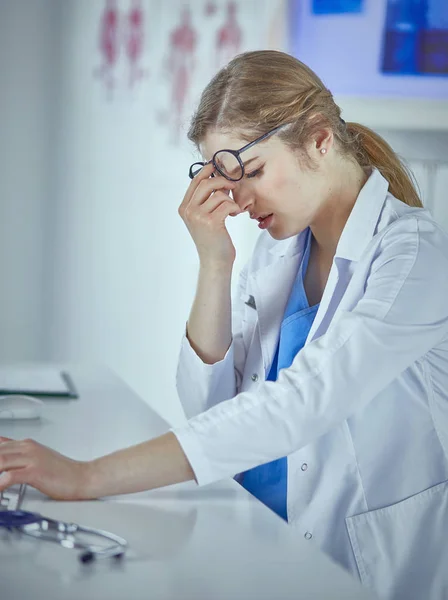 Νεαρή γυναίκα γιατρός κουρασμένη μετά την εργασία με τον υπολογιστή — Φωτογραφία Αρχείου