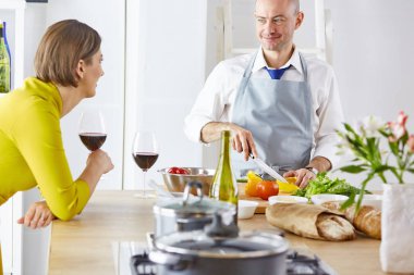 Gülümseyen genç çift mutfakta yemek pişiriyor.