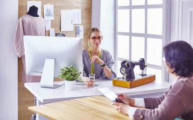 Güzel terzi müşterisine yeni bir tasarım gösteriyor
