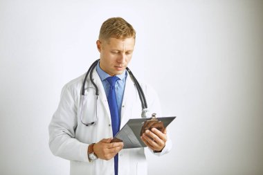 Steteskoplu beyaz önlüklü, kendine güvenen genç bir doktor.