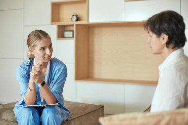 Dost canlısı gülümseyen doktor ve kanepede oturan hasta. Çok iyi haber ve üst düzey tıbbi bakım kavramı.