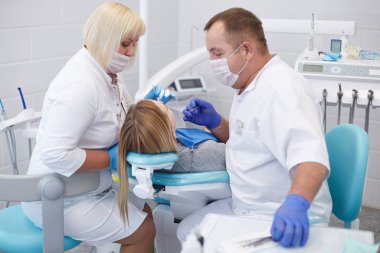 Doktor dişçi genç ve güzel bir kızın dişlerini tedavi ediyor. Dişçinin resepsiyonundaki kız. Doktor dişçi dişleri tedavi eder.