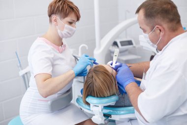 Doktor dişçi genç ve güzel bir kızın dişlerini tedavi ediyor. Dişçinin resepsiyonundaki kız. Doktor dişçi dişleri tedavi eder.