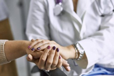 Kadın doktor hastayı sakinleştirir ve elini tutar