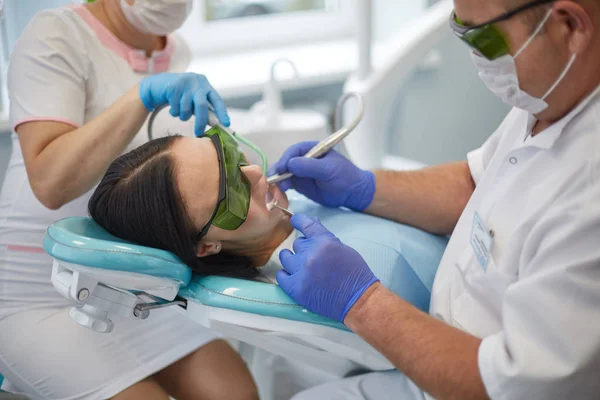 Doctor dentist treats teeth of a beautiful young girl patient. The girl on reception at the dentist. Doctor dentist treats tooth — Stock Photo, Image
