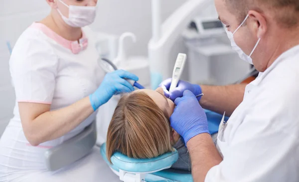 Doctor dentist treats teeth of a beautiful young girl patient. The girl on reception at the dentist. Doctor dentist treats tooth