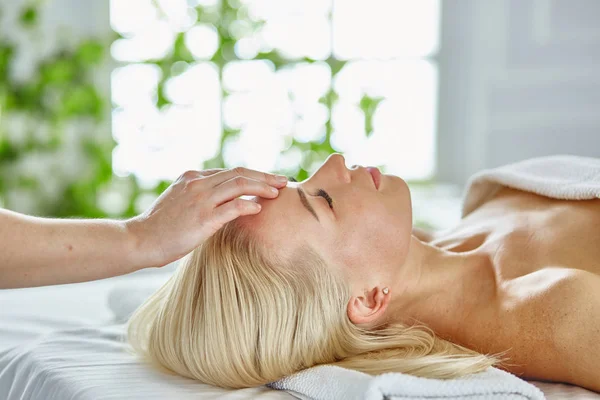 Belle femme aux yeux fermés se faisant masser dans le salon de spa — Photo