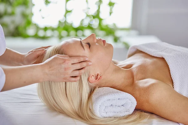 Mulher bonita com olhos fechados recebendo uma massagem no salão de spa — Fotografia de Stock
