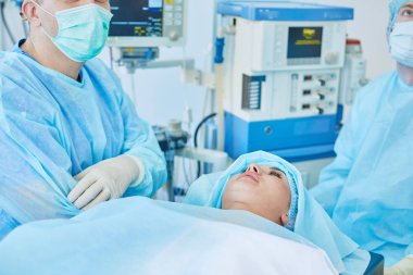 Birkaç doktor hasta operasyon masası üzerinde onların çalışma sırasında çevreleyen. Takım cerrahlar ameliyathane içinde işte