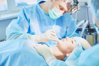 Birkaç doktor hasta operasyon masası üzerinde onların çalışma sırasında çevreleyen. Takım cerrahlar ameliyathane içinde işte